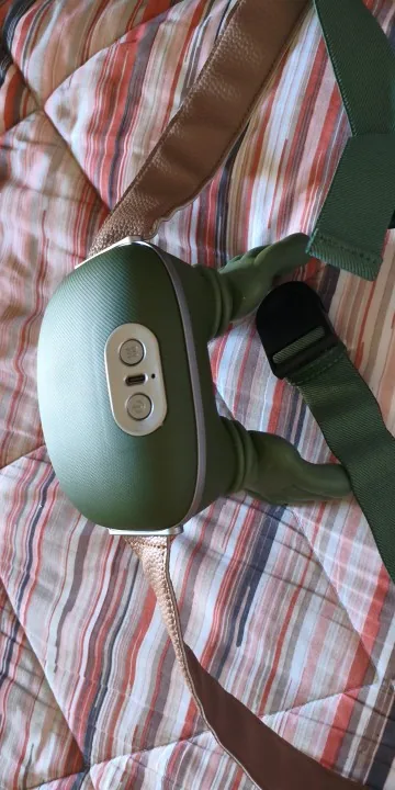 Het massageapparaat op een gestreepte sprei, de bedieningsknoppen zichtbaar op de band